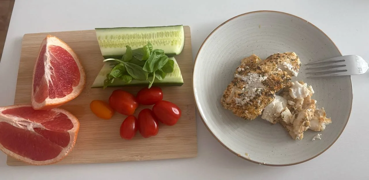 Риба, грейпфрут, огірок і помідори на дошці як приклад корисних продуктів при харчуванні для контролю холестерину