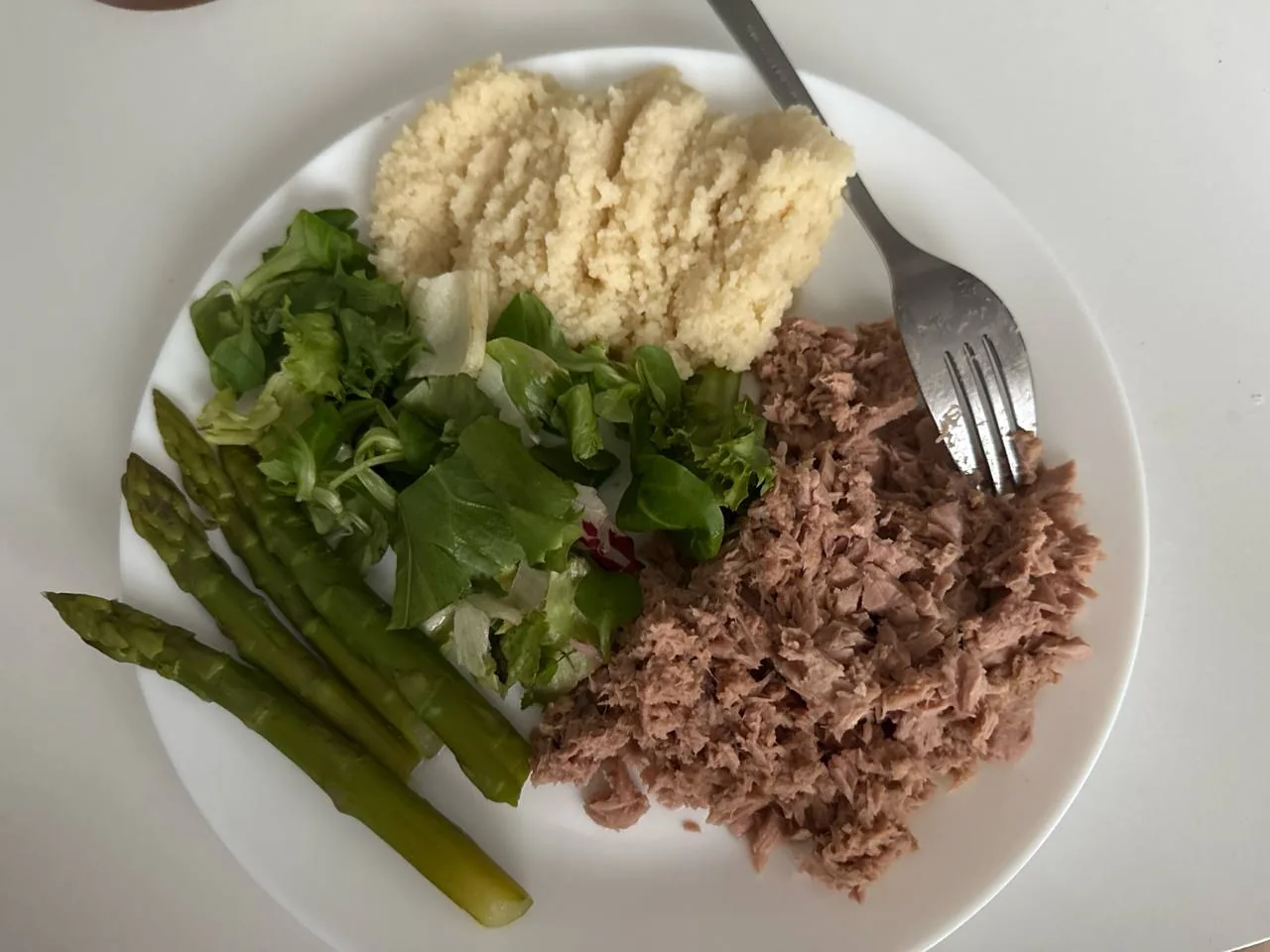 Тарілка з тунцем, кус-кусом, спаржею та зеленню як приклад збалансованого прийому їжі для контролю калорій